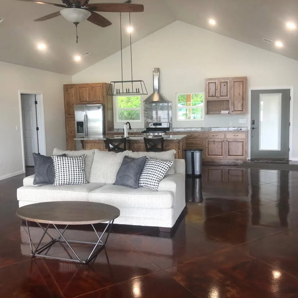 Open concept living room with stained concrete floors and vaulted ceiling